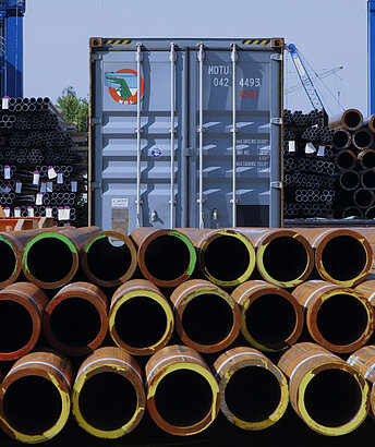 Stacked pipes in front of container